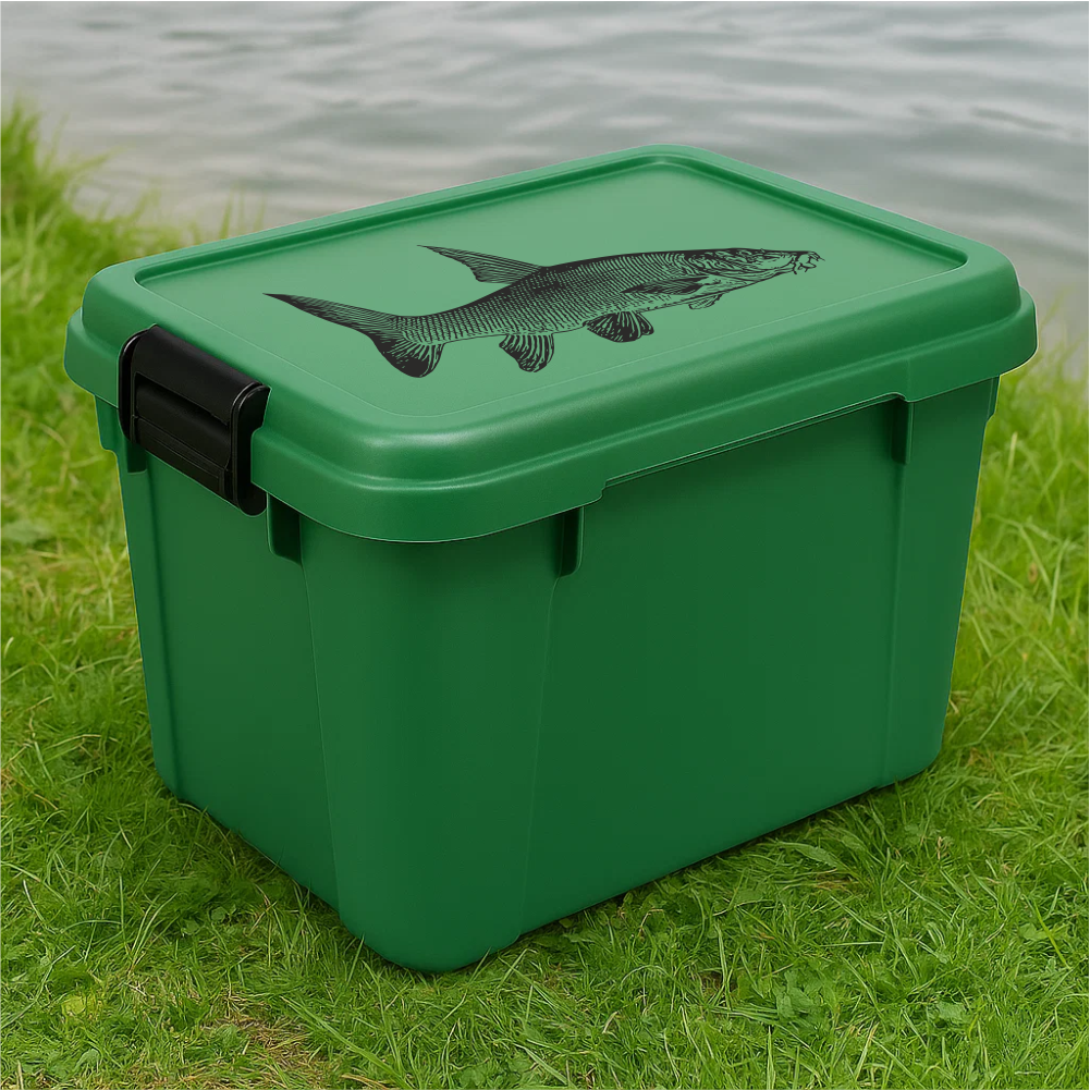 Green plastic fishing storage box with black barbel fish decal – placed on grass by the lake