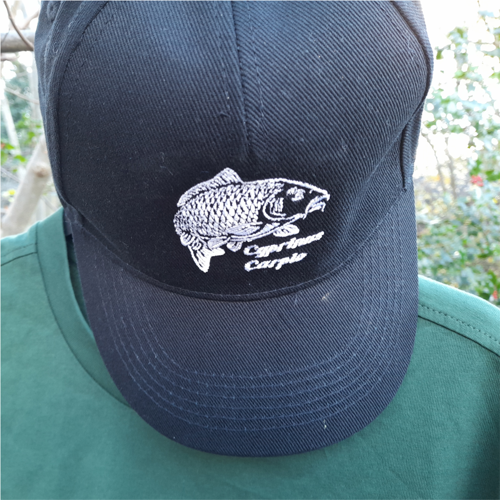 Close-up of black fishing cap with embroidered carp design worn outdoors