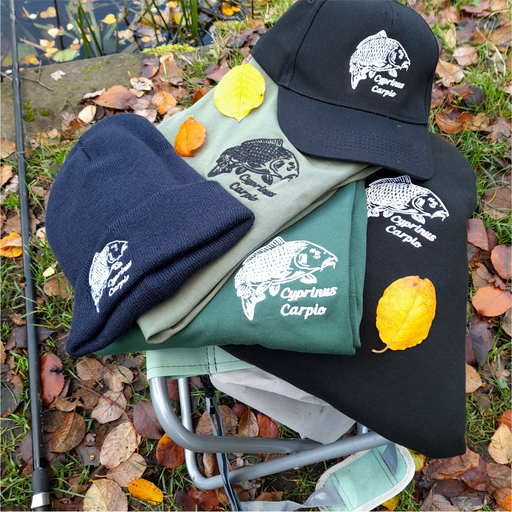Fishing apparel bundle including embroidered cap, beanie, t-shirts and hoodie arranged outdoors with autumn leaves