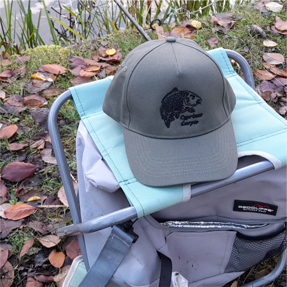 Olive carp fishing cap on chair outdoors – embroidered angler cap for carp fishermen