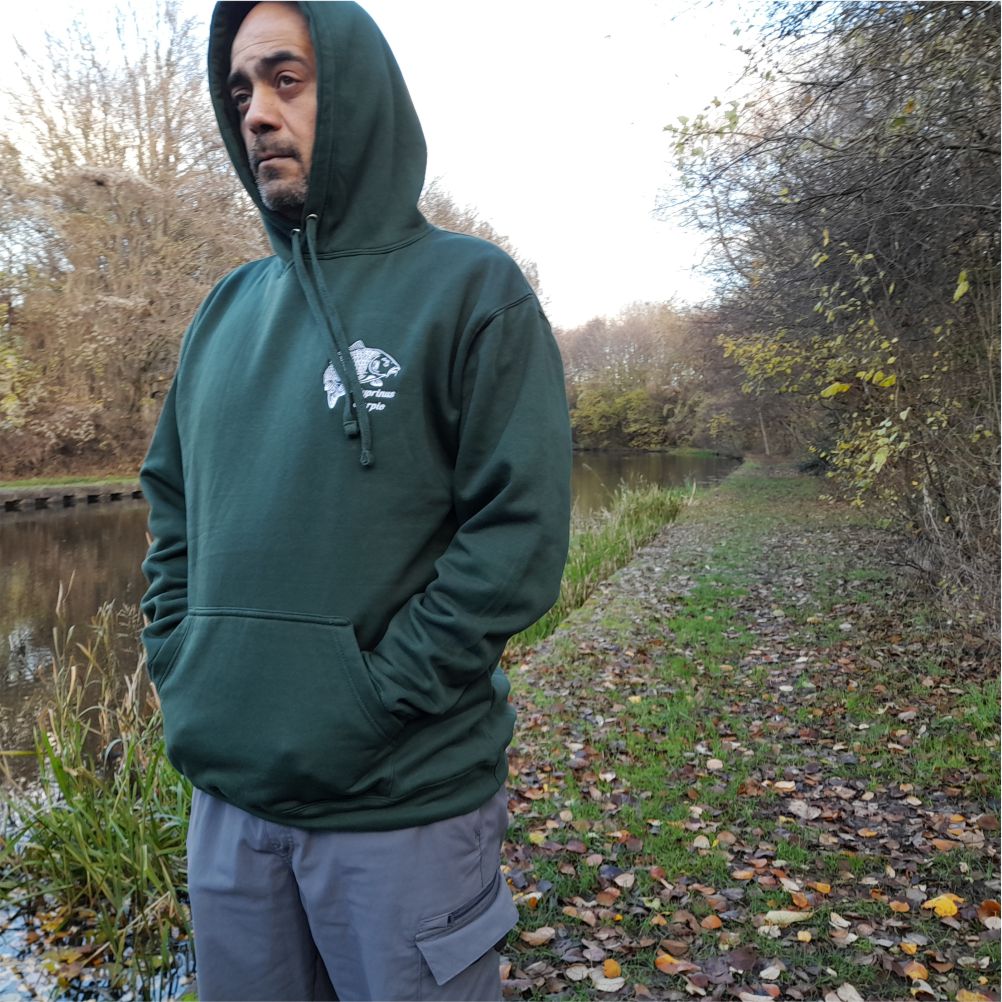 Angler wearing forest green carp embroidered hoodie by the bank – warm fishing hoodie for carp anglers