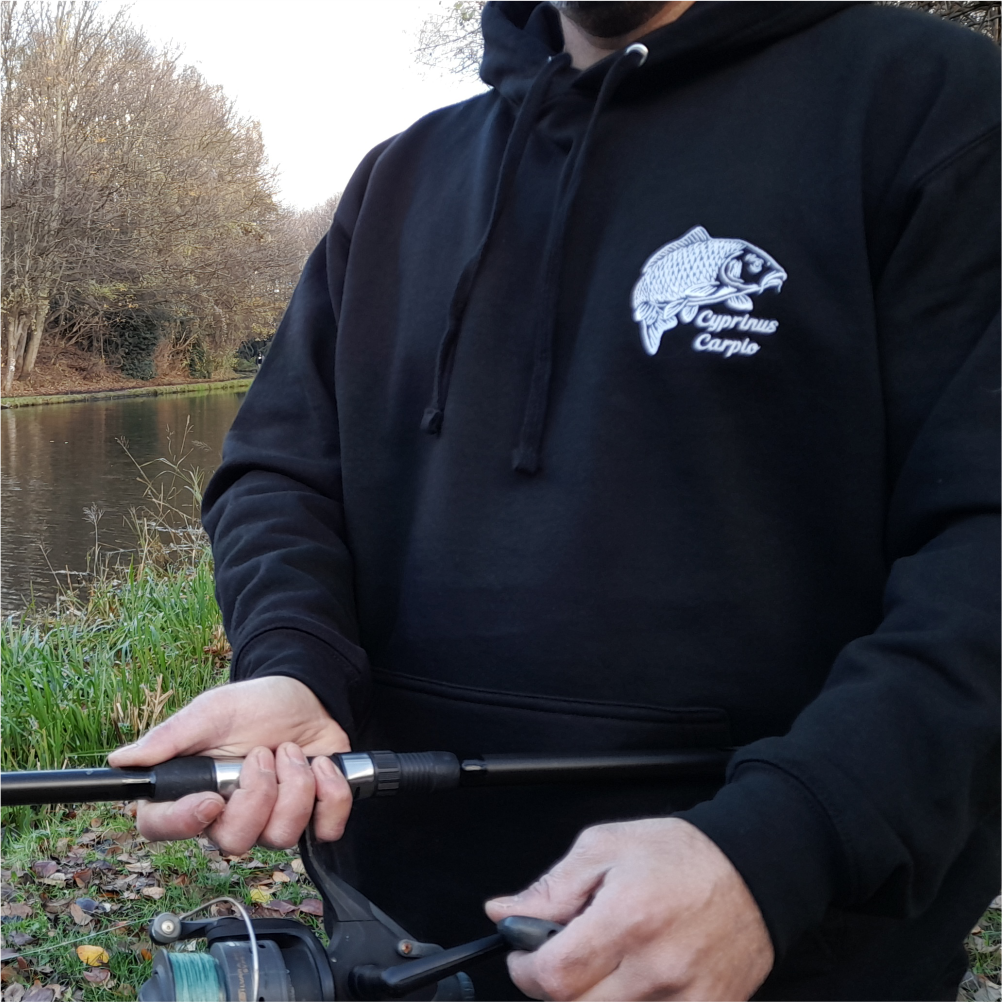 Man wearing black carp embroidered hoodie while fishing – lifestyle angling apparel